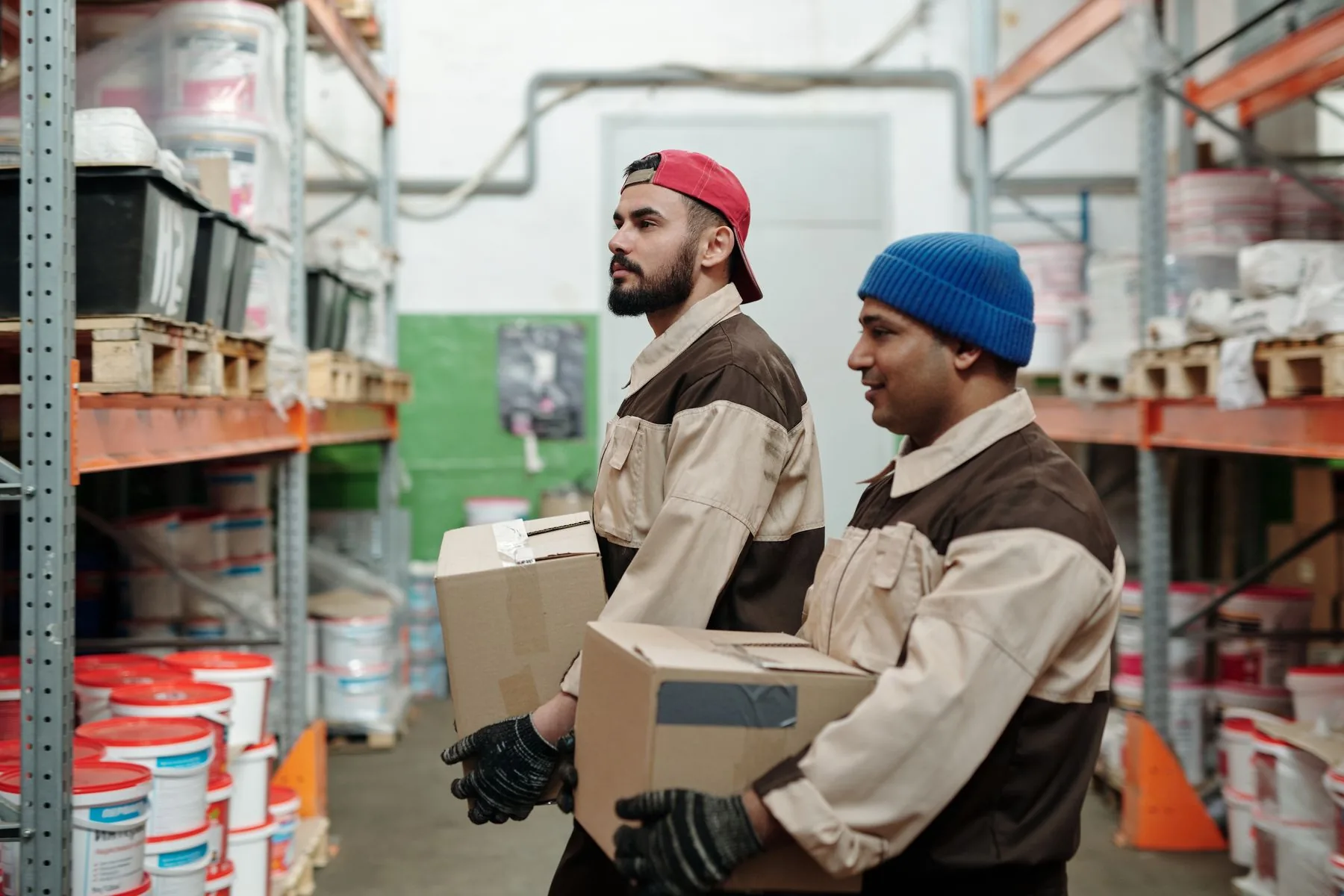 Warehouse workers carrying boxes between storage shelves